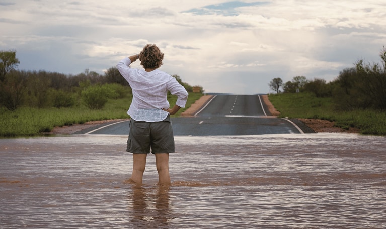 Woman stands in flooded street.