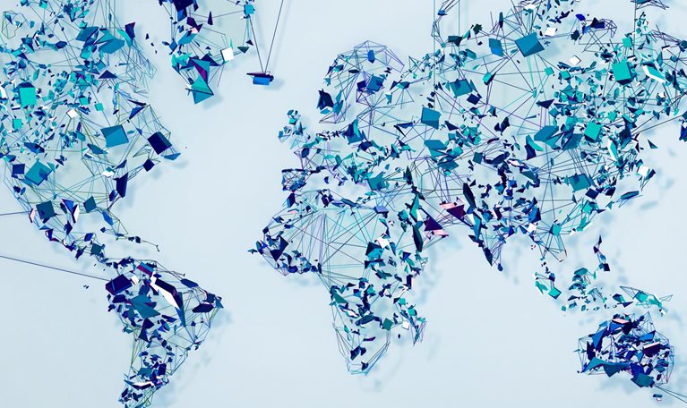 A world map made up of geometric shapes resembling shards of glass and thin lines connecting them.