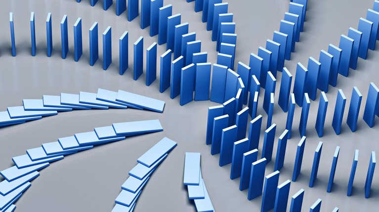 An array of dominoes cascading in a chain reaction on a blue backdrop