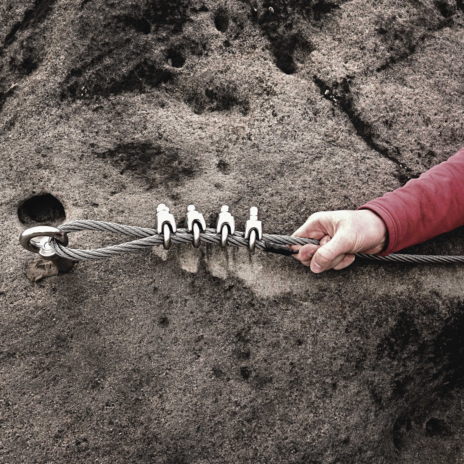 Rock climber holding on to steel twisted rope