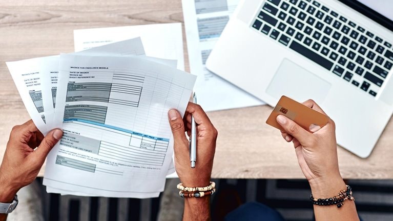 High-angle shot of a young using a credit card while going over their finances at home
