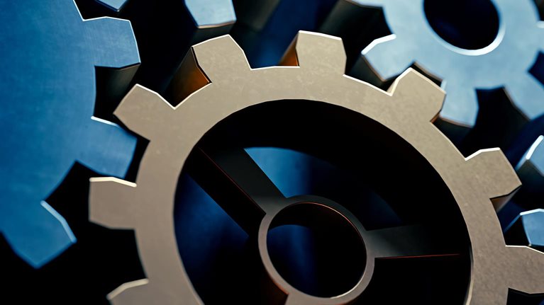 Shadowed image of blue and gold gears moving in a machine