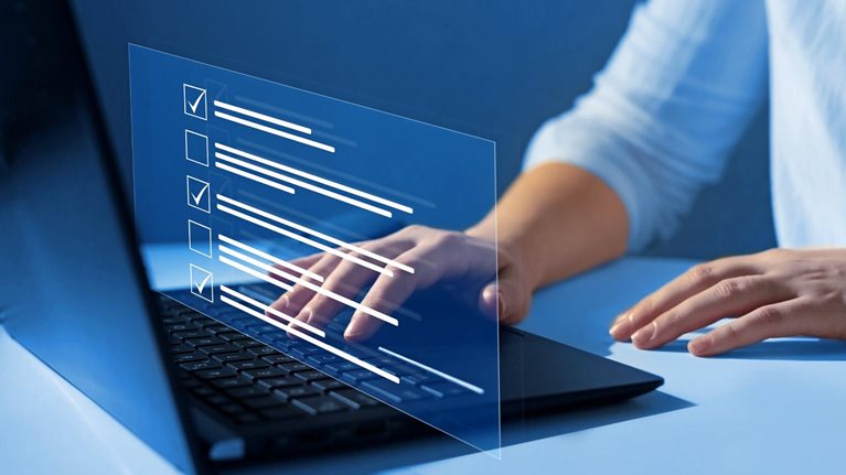 Close up of a woman's hands on a laptop keyboard. A representation of a screen display floats over her hands showing boxes getting checked off as she answers quiz questions.