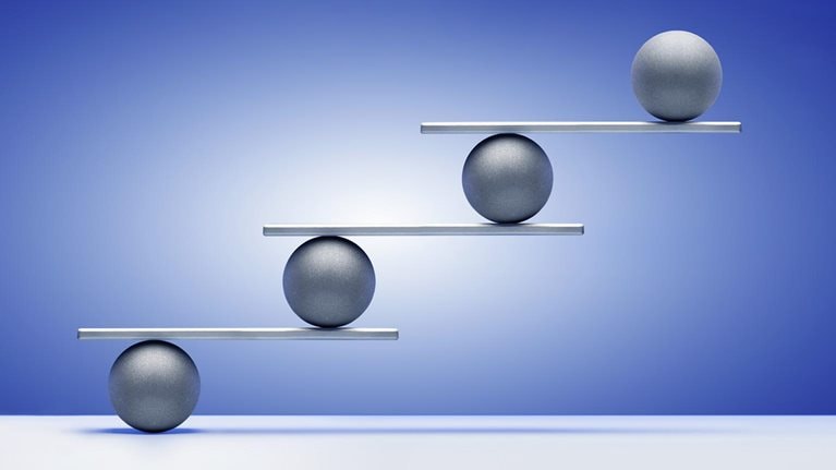Silver colored balls on ascending white shelves, gradated blue background