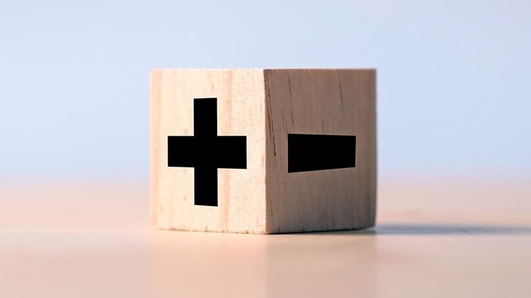 A wooden block marked with a positive and negative sign