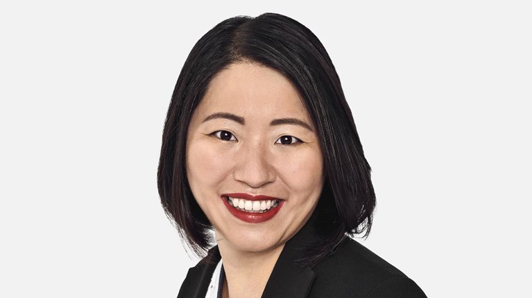 Portrait of Marjorie Lao with a bright smile and wearing a suit jacket over a fine knit top.