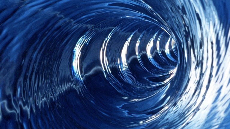 Swirling blue waters being drawn in at great speed making a conical whirlpool shape