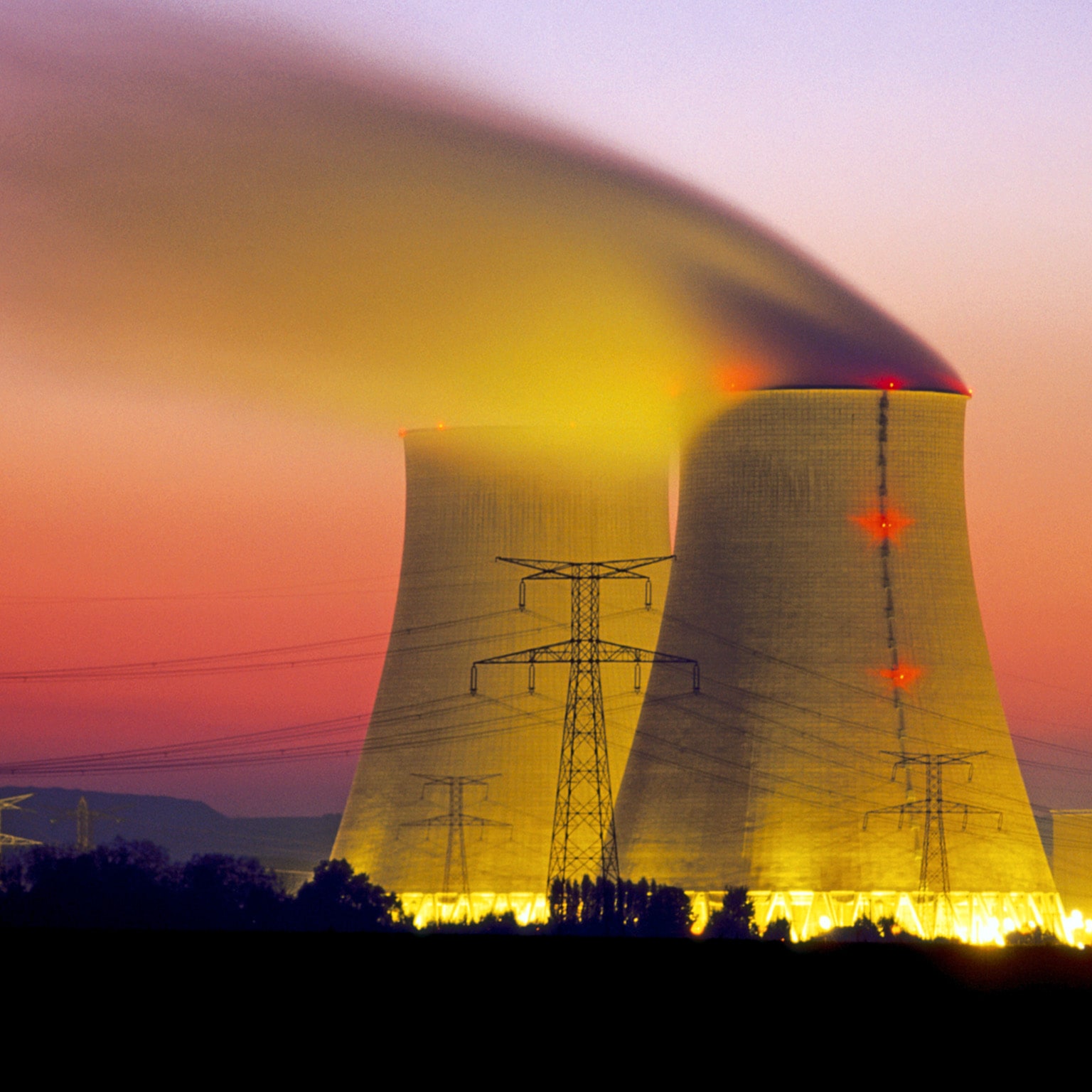 Two nuclear power plant stacks with high power lines at dusk. The sky is a moody purple and red gradient, and the stacks are light with a fluorescent yellow glow.