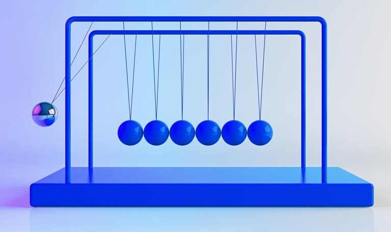 Newton's Cradle, with shiny, metallic balancing balls. Six remain still as one is in motion.