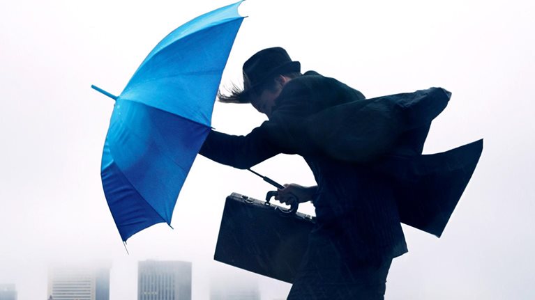 Businessman with umbrella in the wind