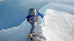 A lone climber ascending a snowy ridge in the Alps