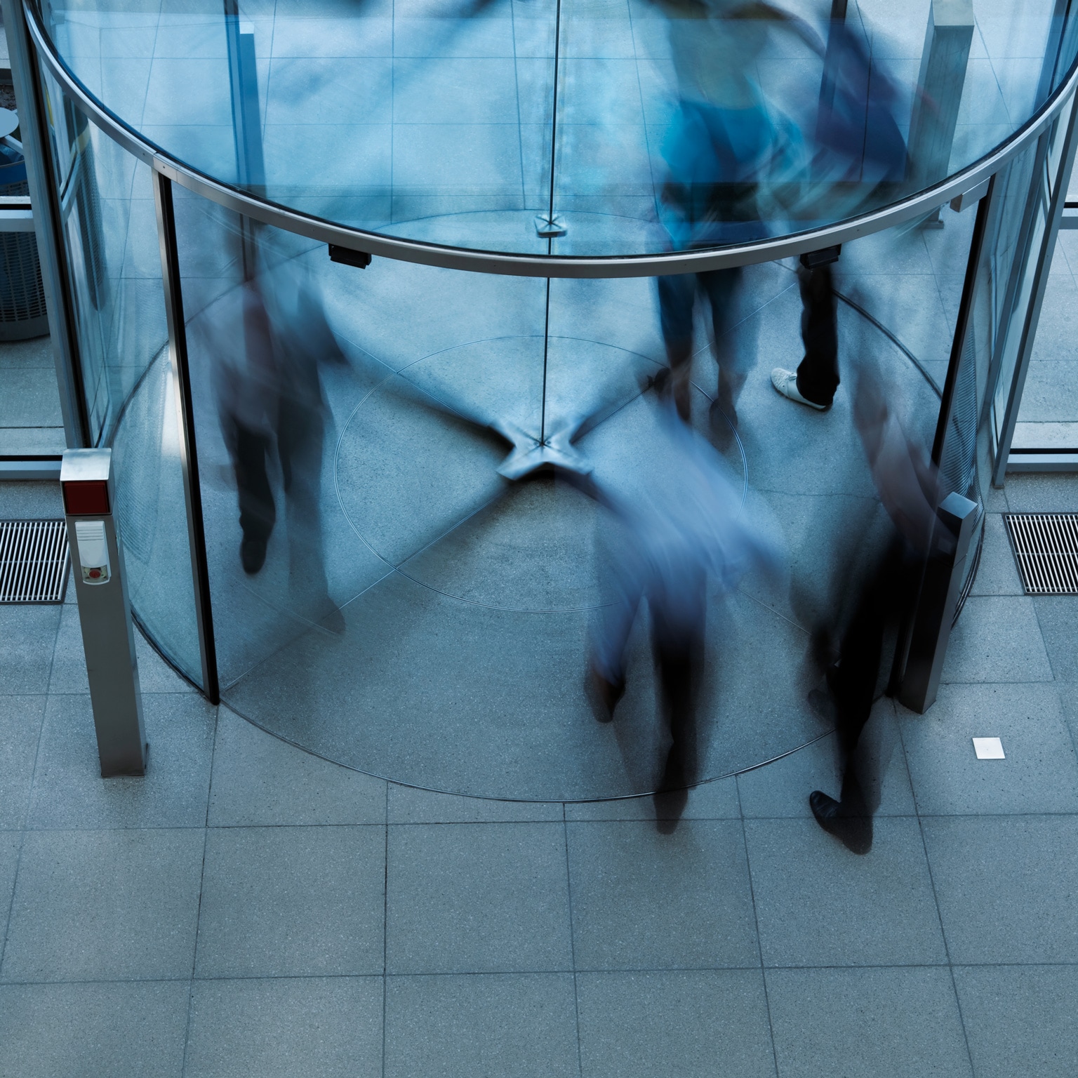 Blurry image of people walking through a revolving door