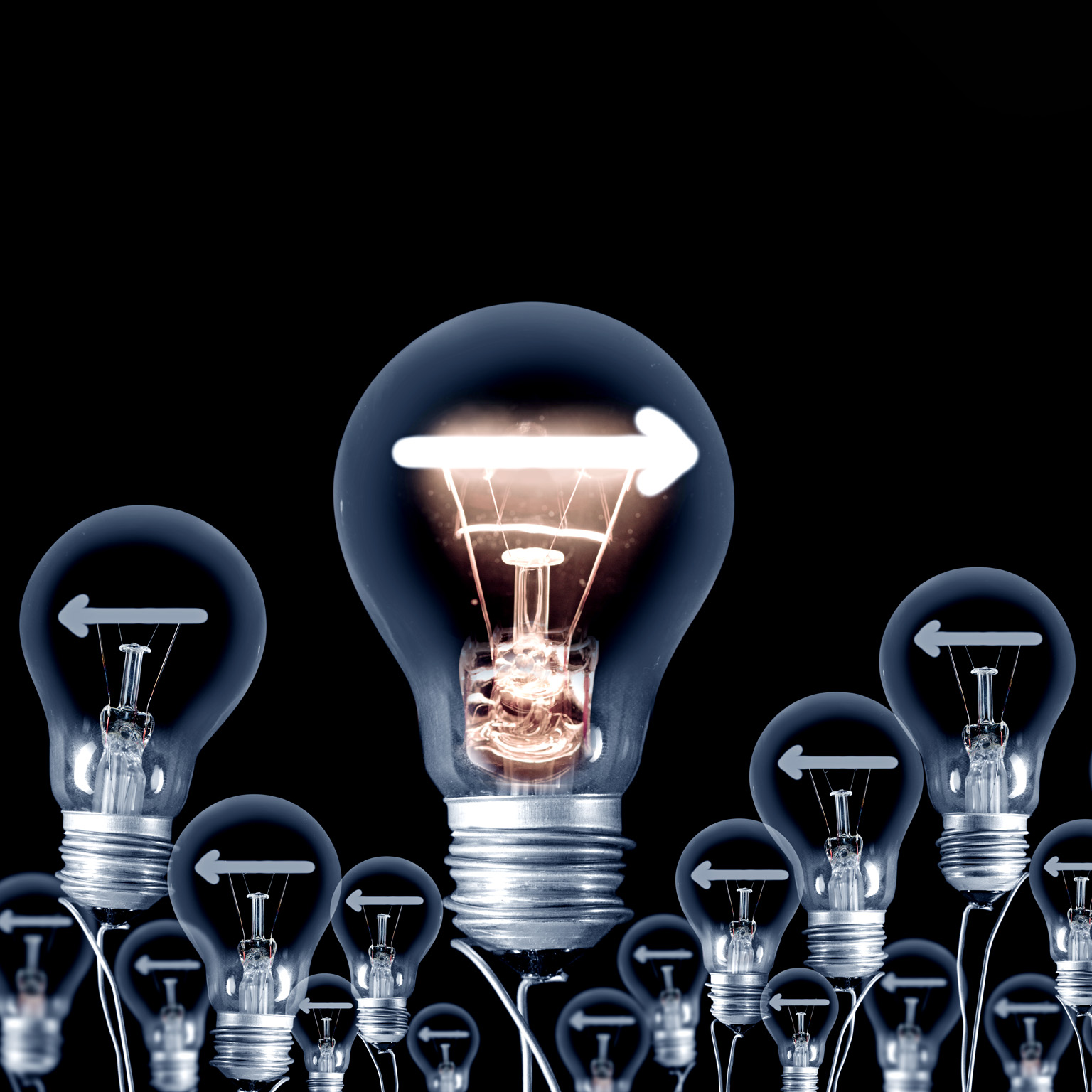 A group of light bulbs set on a dark backdrop. All of the bulbs display a left-facing arrow, except for one bulb that stands out with a right-facing arrow and is illuminated.