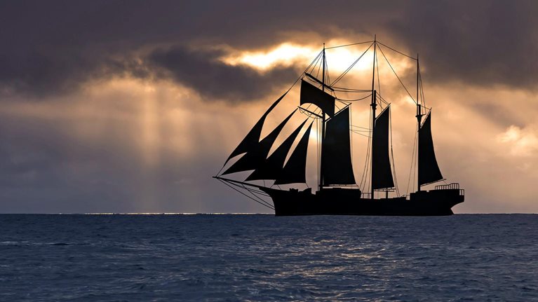 Image of a sailboat at sunset in a stormy sea.