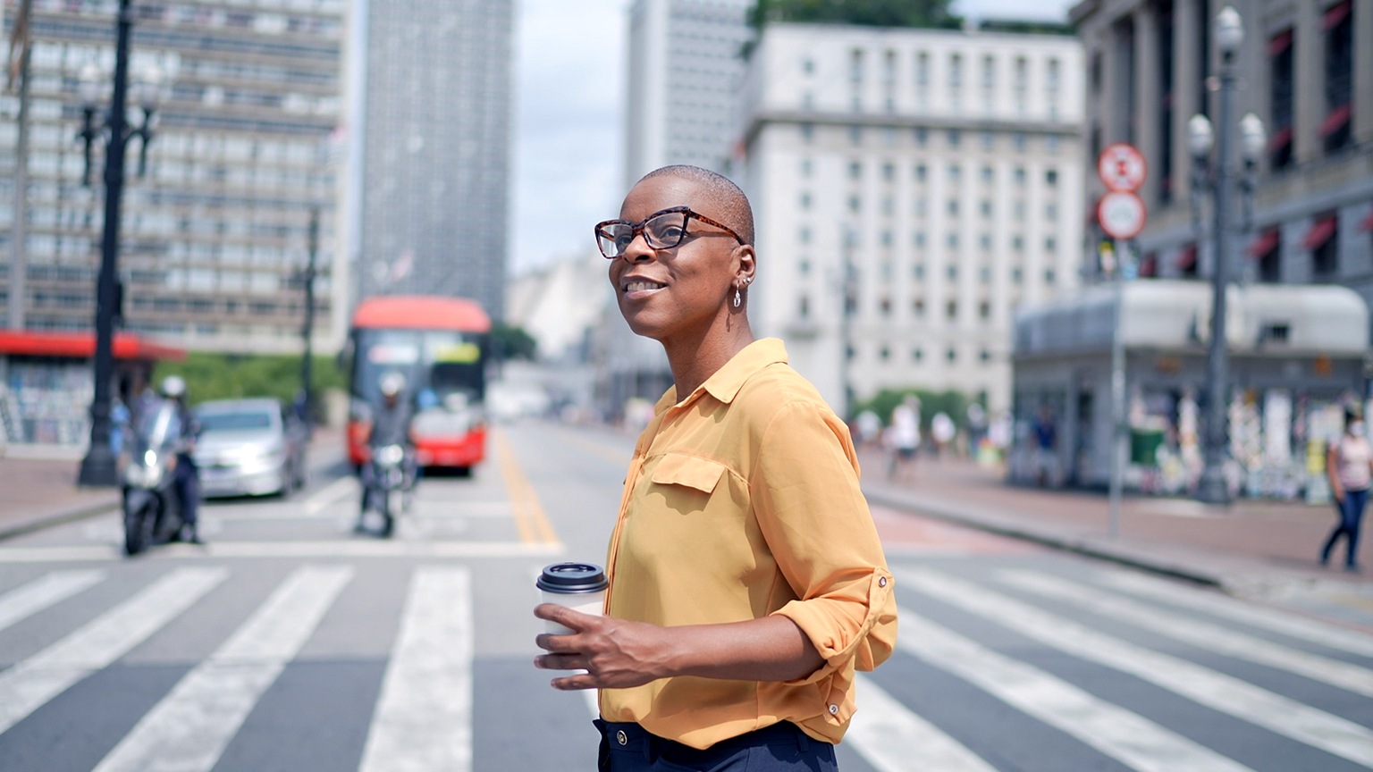 A person crossing the street holding a coffee cup