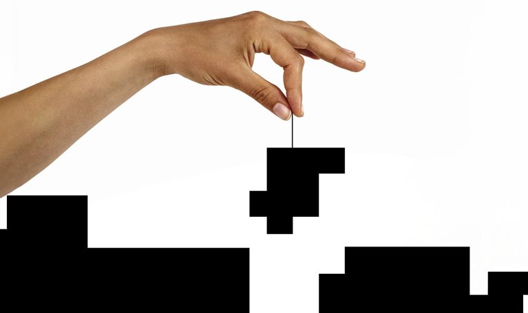 Conceptual image of a hand lowering a puzzle piece into a black and white puzzle.