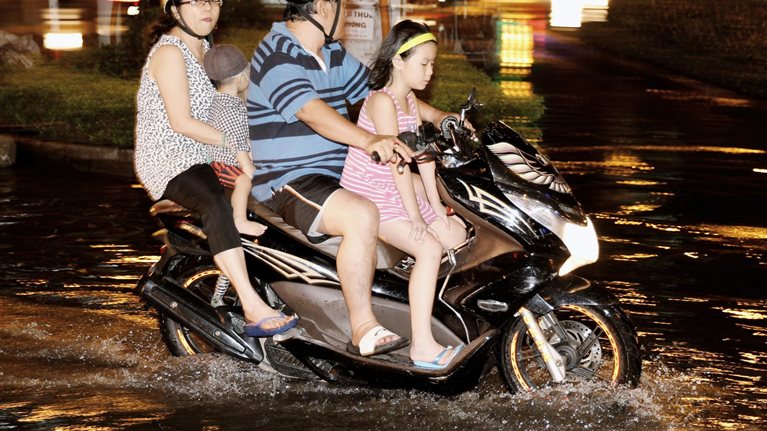 People on a motorbike in a flood zone