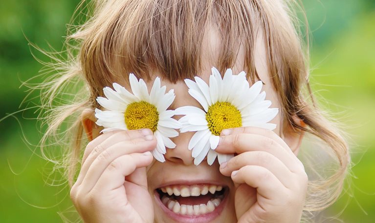 The girl is holding chamomile flowers in her hands