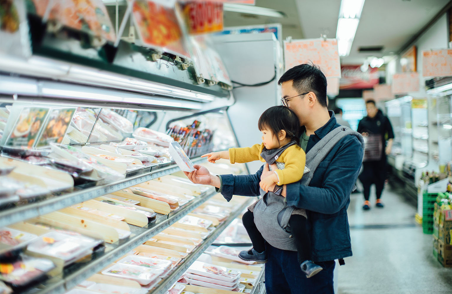 Man holding toddler perusing grocery aisle