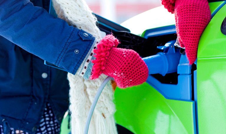 Young woman charging electric car - stock photo