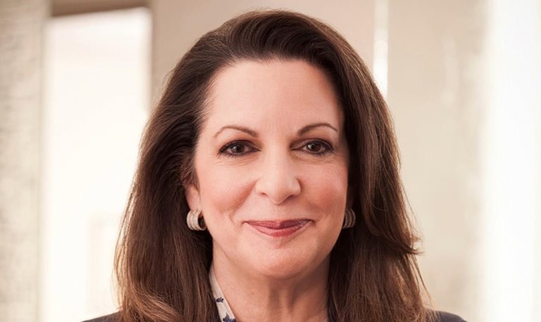 A professional headshot of Julia Stewart. She has long dark brown hair and is wearing a dark blazer over a patterned blouse while smiling gently.