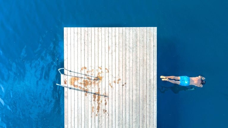 Aerial view of a man jumping from a floating dock into a blue lake
