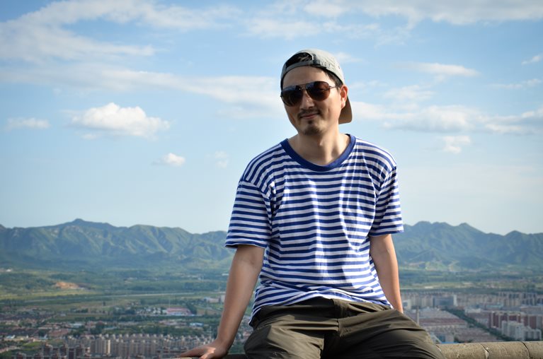 Mingming sitting on ledge with mountains in background