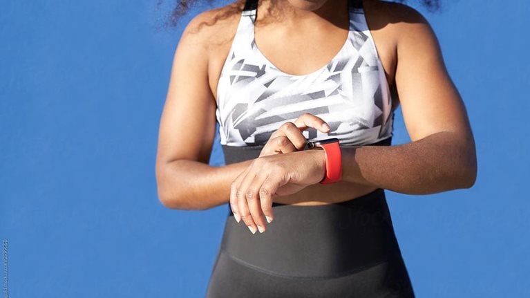 A photo of a person looking at their fitness monitor strapped to their wrist.
