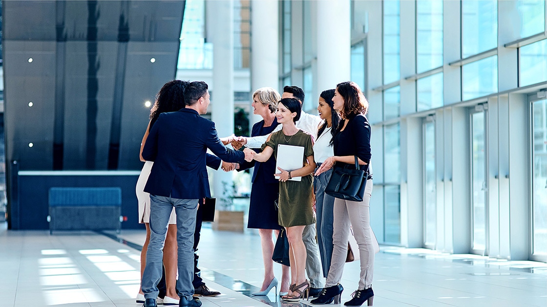 Image of coworkers shaking hands in a large office complex
