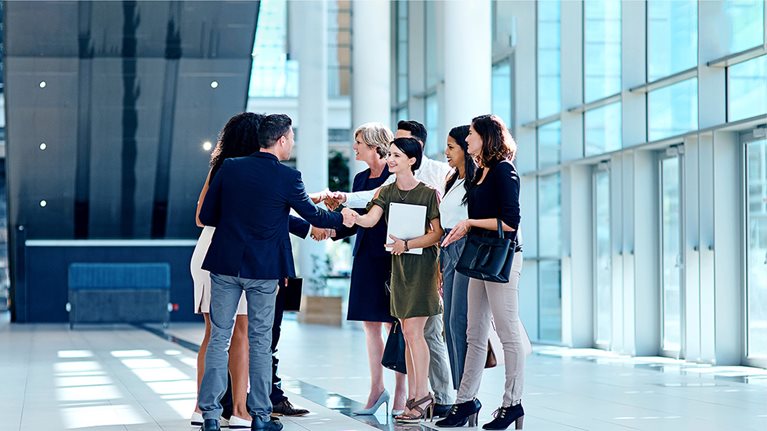 Image of coworkers shaking hands in a large office complex