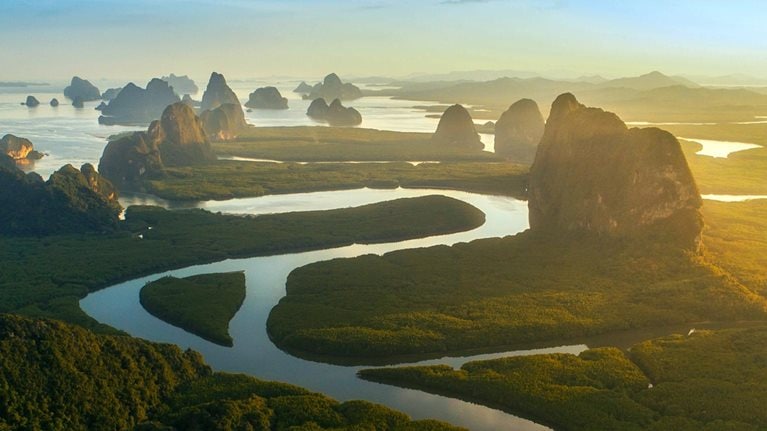 A horizon line view of the limestone cliffs and rock formations of Phang Nga Bay in Thailand.