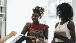 Two customers paying at counter in a coffee bar