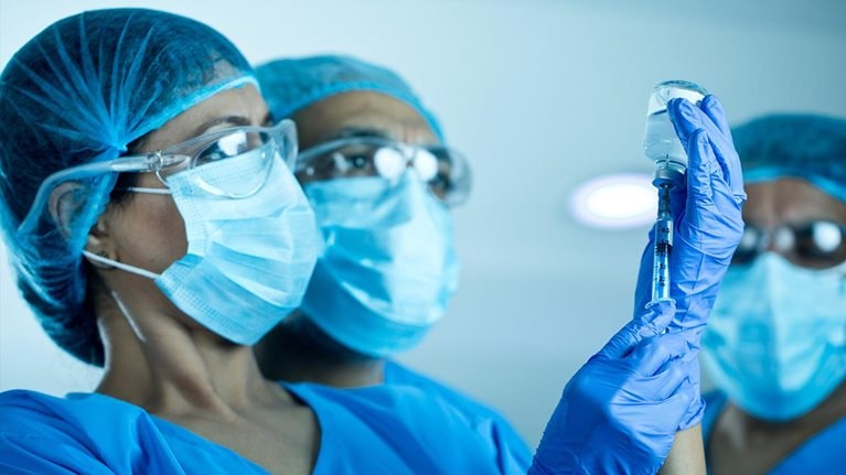 Doctors team preparing injection with COVID-19 vaccine - stock photo