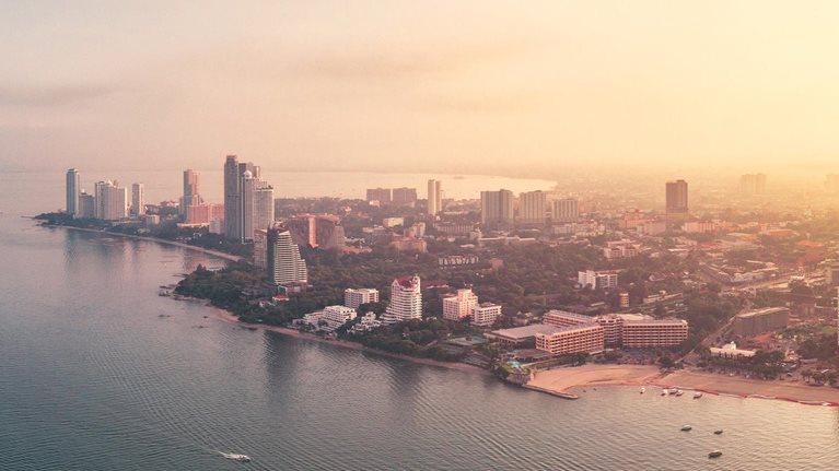 Dramatic drone panoramic photo with sunrise cityscape view of the Pattaya City, Thailand and the ocean around it. - stock photo