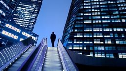 Businessman on top of moving escalator at illuminated business district - stock photo