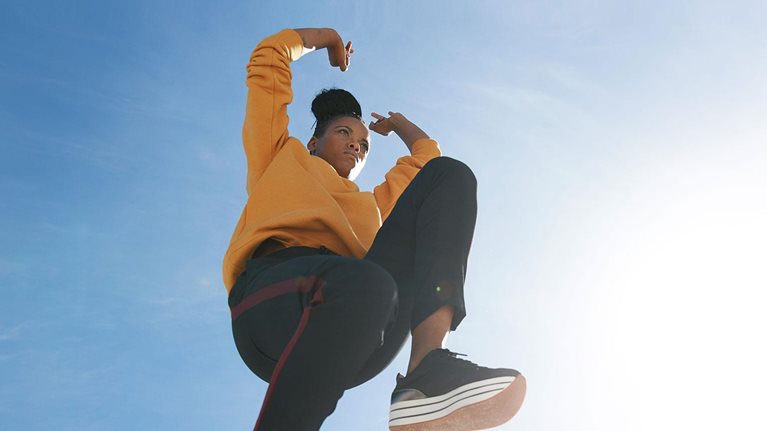 A young woman jumping with a bright sky in the background