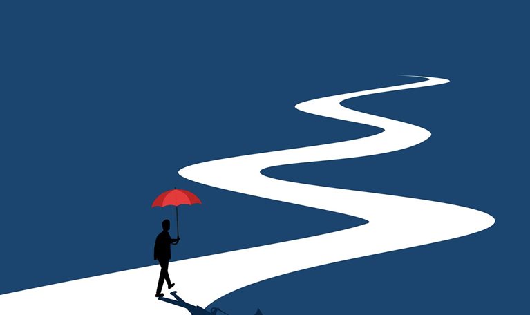 Businessman walks along a long, winding road holding an umbrella.