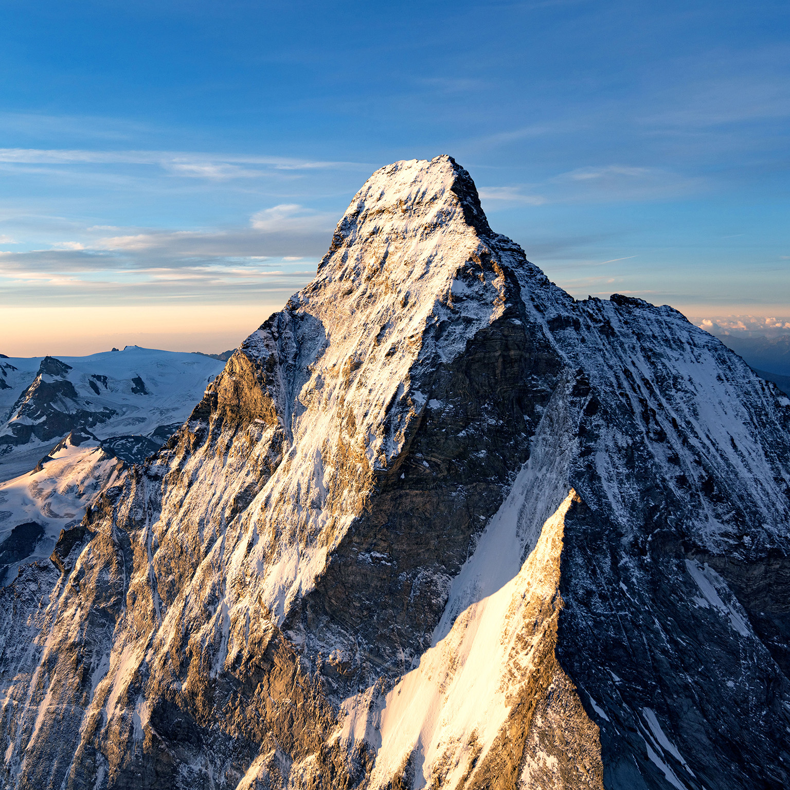 A snow covered mountain peak against a blue sky.