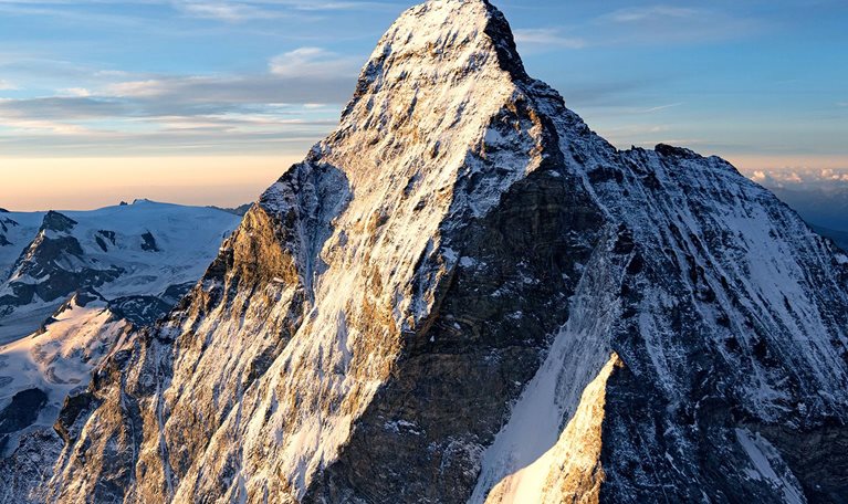 A snow covered mountain peak against a blue sky.