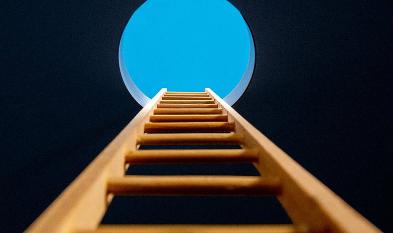 Point of view, looking up ladder sticking through hole in ceiling revealing blue sky