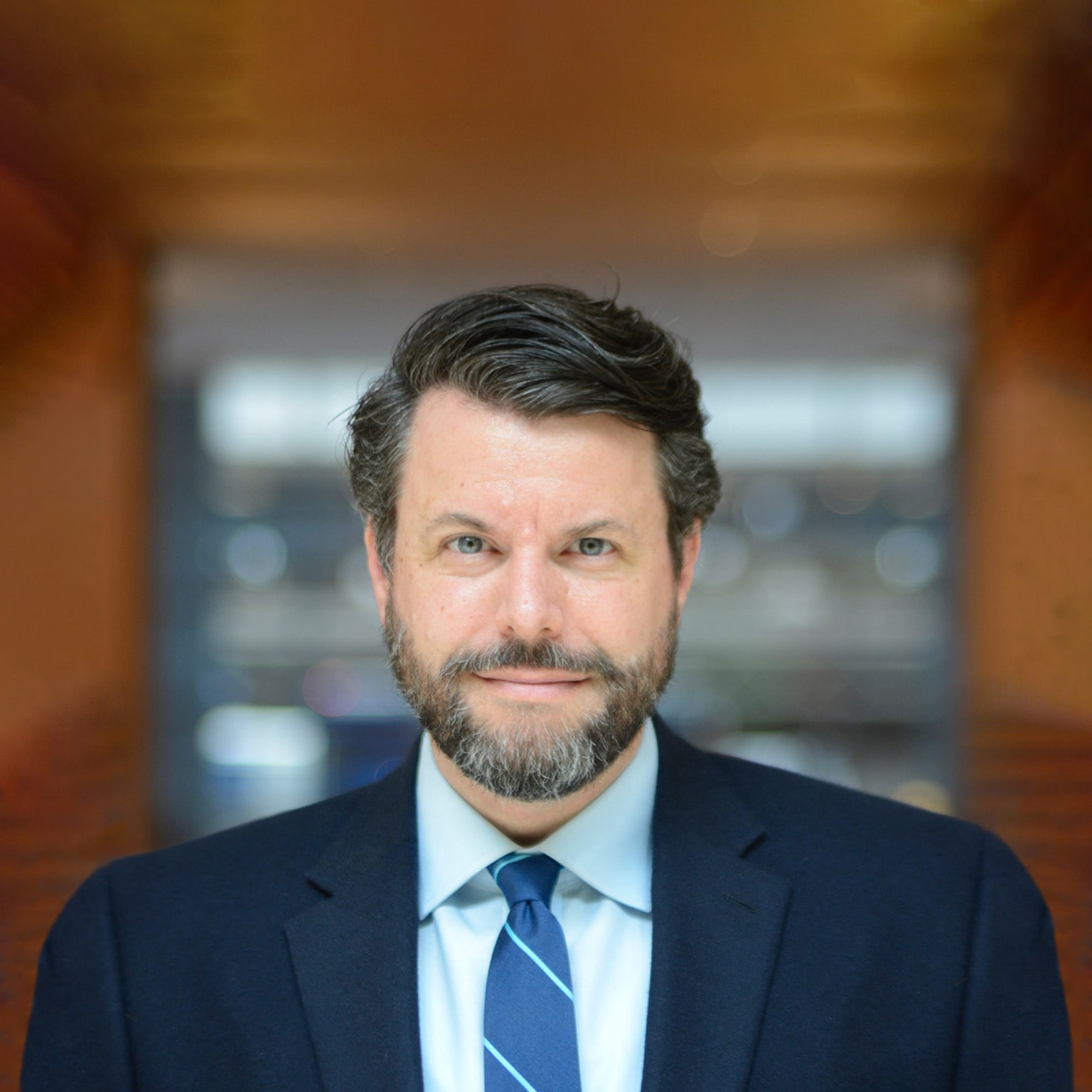 Portrait of author Charles Duhigg with a subtle smile and in a navy blue suit. 