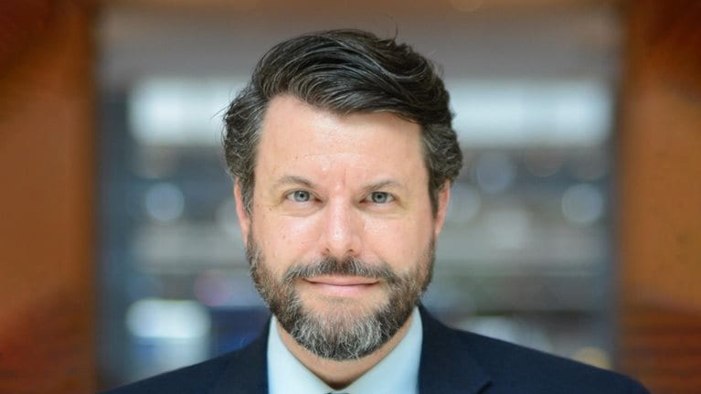 Portrait of author Charles Duhigg with a subtle smile and in a navy blue suit.