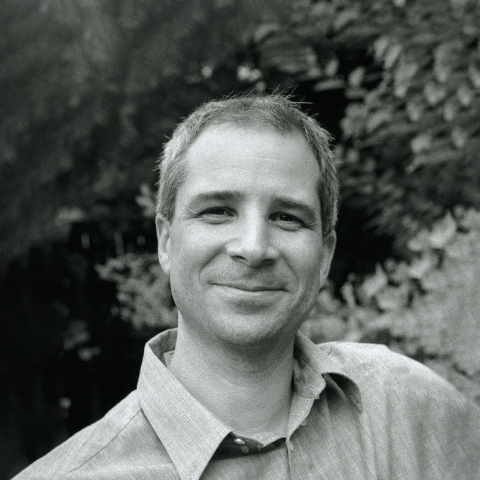 Black and white portrait of a smiling Howard Friedman photographed outdoors.