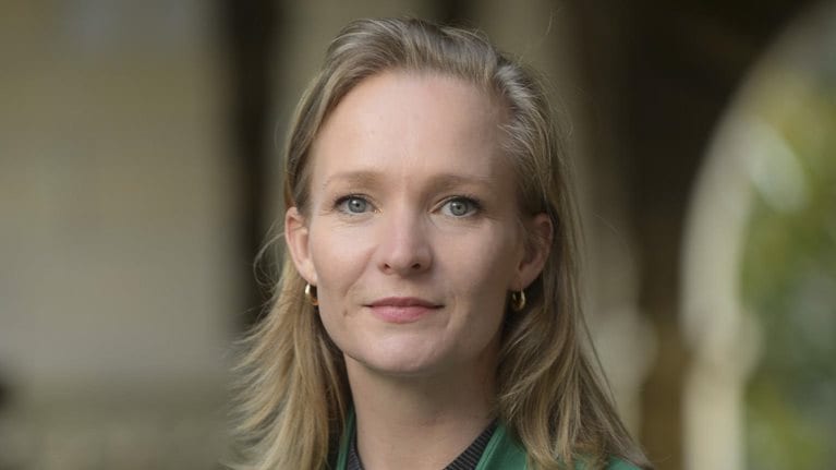 Marietje Schaake is depicted in a green blazer, with a subtle smile and a confident gaze.