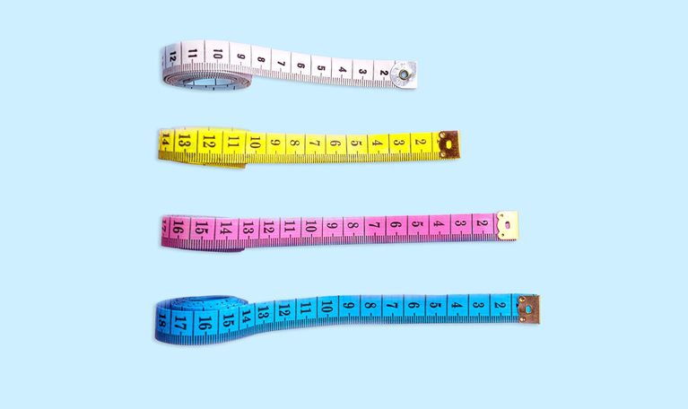Four measuring tapes are positioned vertically on a light blue backdrop. Each tape is stretched out to varying lengths and placed in increasing order from the longest to the shortest.