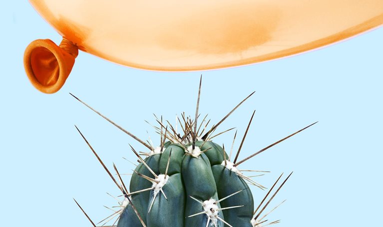 A balloon flying dangerously close to a cactus.
