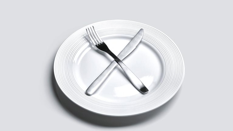 Empty plate with knife and fork in cross shape