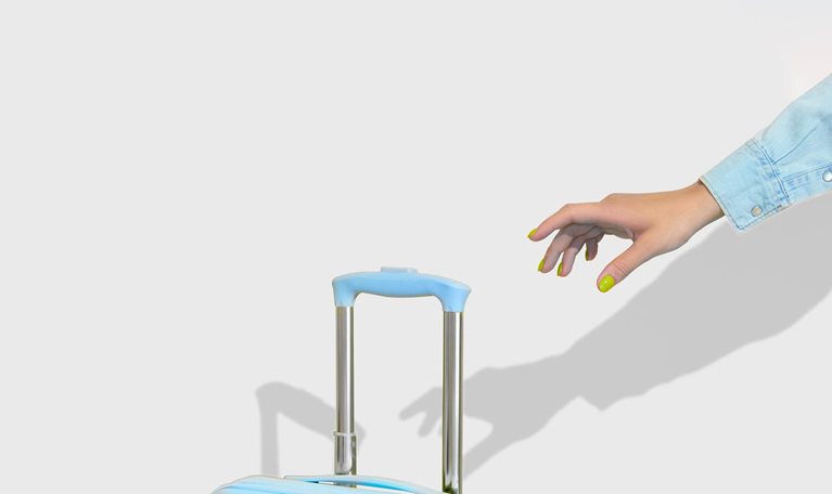 A hand with bright yellow nails reaches for the handle of a blue suitcase.