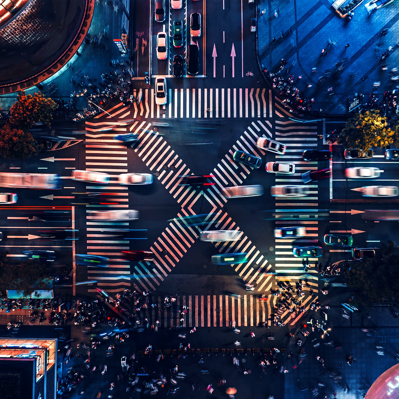 Overhead view of large roadway crosswalk section with heavy volume of cars passing in various directions.