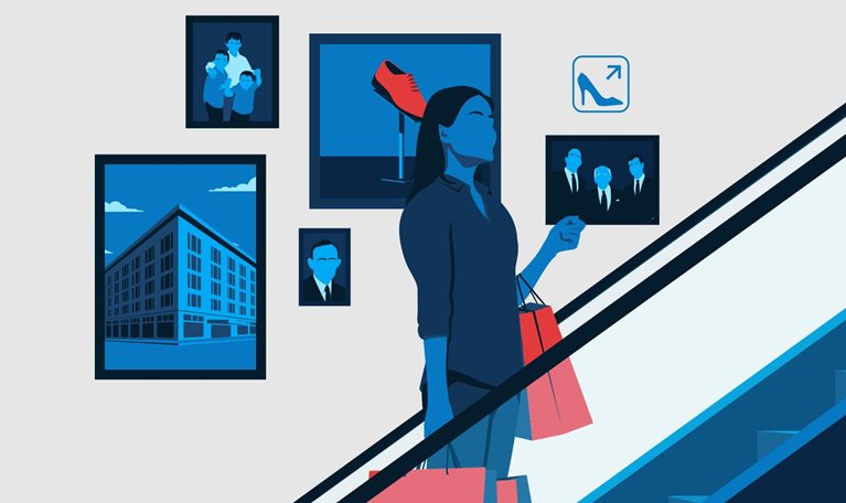 A woman holding shopping bags travels up the escalator of a department store. Behind her are photos representing the life of the store's owner.